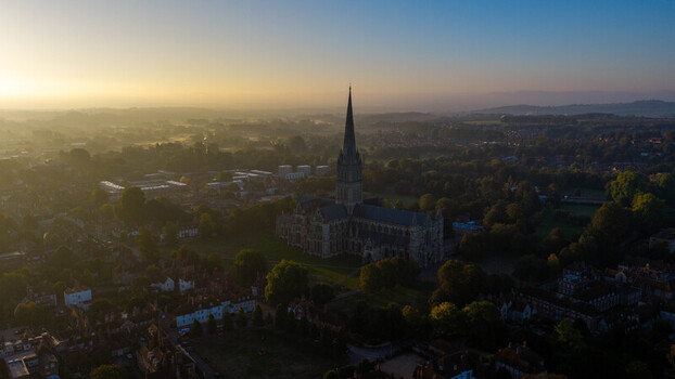 Aerial view of Salisbury Cathedral surrounded by lush greenery and historic buildings in the morning light in Salisbury England United Kingdom. Aerial view of Salisbury Cathedral surrounded by lush greenery and historic buildings in the morning light in Salisbury England United Kingdom.