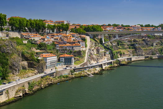 Aerial view of terracotta rooftops cascade down the hillside towards the Douro River with the Arrábida Bridge gracefully arching above Porto Porto District Portugal. Aerial view of terracotta rooftops cascade down the hillside towards the Douro River with the Arrábida Bridge gracefully arching above Porto Porto District Portugal.