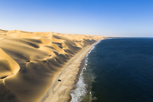 Aerial view of the stark contrast between the towering sun kissed dunes and the endless deep blue ocean Anichab Erongo Namibia. Aerial view of the stark contrast between the towering sun kissed dunes and the endless deep blue ocean Anichab Erongo Namibia.