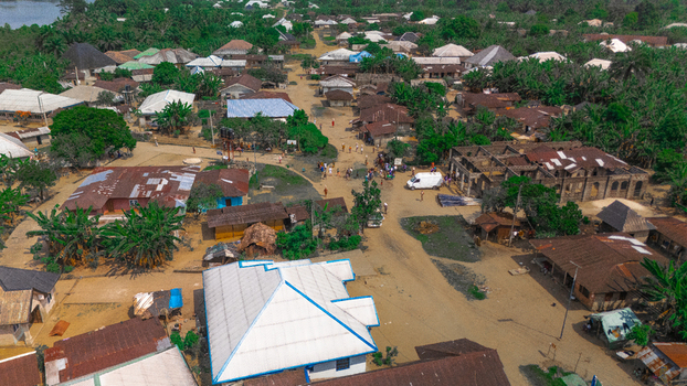 Aerial view of the village featuring traditional houses with metal rooftops dirt roads lush vegetation and local residents in Abua Rivers Nigeria. Aerial view of the village featuring traditional houses with metal rooftops dirt roads lush vegetation and local residents in Abua Rivers Nigeria.