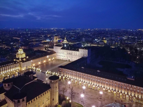 Aerial view of Palazzo Reale and Piazza Castello illuminated at night under a deep blue twilight sky in Turin Piedmont Italy.