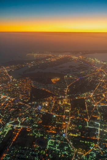 Aerial view of the illuminated cityscape of Karachi at night featuring the sprawling urban grid glowing street lights and the coastline along the Arabian Sea in Karachi Sindh Pakistan.