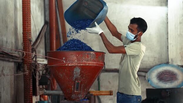 View of a worker pouring plastic flakes in Bogura Bangladesh. View of a worker pouring plastic flakes in Bogura Bangladesh.