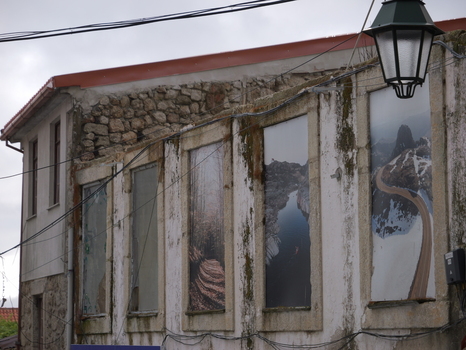 View of large photographic landscape prints mounted on the weathered stone wall of an old building in the historic center of Covilha Castelo Branco District Portugal.
