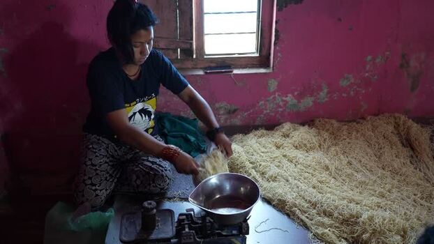 View of a woman weighing noodles in a workshop Nepal. View of a woman weighing noodles in a workshop Nepal.