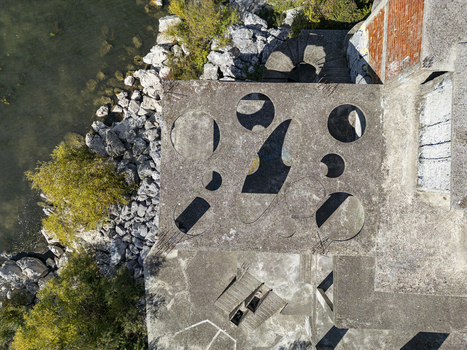 Aerial view of an abandoned concrete structure featuring circular cutouts and exposed rebar situated on the rocky shoreline of Lake Shkoder in Shiroka Shkoder County Albania. Aerial view of an abandoned concrete structure featuring circular cutouts and exposed rebar situated on the rocky shoreline of Lake Shkoder in Shiroka Shkoder County Albania.