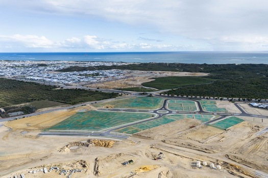 Aerial view of a new residential development site with newly paved roads roundabouts and green erosion control netting on plots near the coast in Perth Western Australia Australia. Aerial view of a new residential development site with newly paved roads roundabouts and green erosion control netting on plots near the coast in Perth Western Australia Australia.