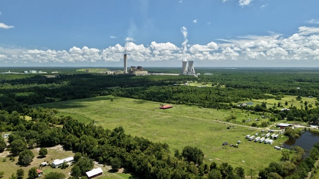 Aerial view of the Seminole Electric Fuel Tanks power plant with cooling towers and smokestacks rising above the surrounding forest and green fields in Palatka Florida United States.