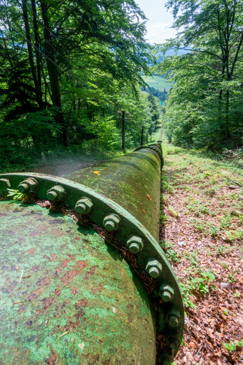 View of the historic penstock of the Jasenie Hydroelectric Power Plant stretching through a lush green forest in Jasenie Banska Bystrica Regio Slovakia.