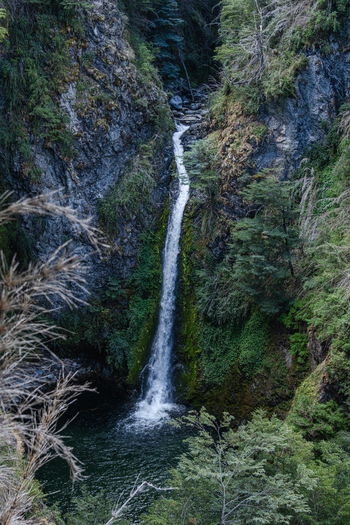 View of Waterfall Rio Bonito cascading down a rocky cliff surrounded by lush green forest and vegetation in Los Lagos Department Neuquen Province Argentina. View of Waterfall Rio Bonito cascading down a rocky cliff surrounded by lush green forest and vegetation in Los Lagos Department Neuquen Province Argentina.