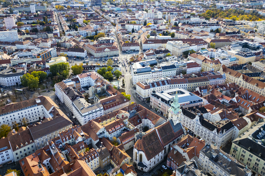 Aerial view of terracotta rooftops blending with the city s golden autumn hues punctuated by the clock tower Graz Styria Austria.