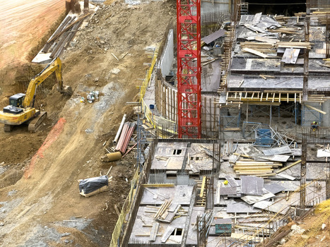 Aerial view of a busy construction site featuring a yellow excavator a red tower crane and concrete foundations in Sariyer Istanbul Turkiye. Aerial view of a busy construction site featuring a yellow excavator a red tower crane and concrete foundations in Sariyer Istanbul Turkiye.