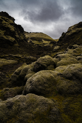 View of moss covered rocks leading to a distant hill under a dramatic overcast sky Skaftárhreppur Skaftárhreppur Iceland. View of moss covered rocks leading to a distant hill under a dramatic overcast sky Skaftárhreppur Skaftárhreppur Iceland.