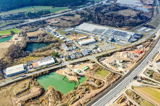 Aerial view of the industrial area and commercial warehouses near a quarry with a green pond and surrounding fields in Buttenheim Bavaria Germany. Aerial view of the industrial area and commercial warehouses near a quarry with a green pond and surrounding fields in Buttenheim Bavaria Germany.