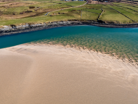 Aerial view of Ballyness Bay featuring intricate tidal sand patterns turquoise water and surrounding green fields with stone walls in Ballyness County Donegal Ireland. Aerial view of Ballyness Bay featuring intricate tidal sand patterns turquoise water and surrounding green fields with stone walls in Ballyness County Donegal Ireland.