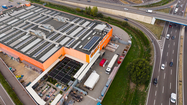 San Giuliano Milanese Italy 25 September 2026 Aerial view of the OBI store featuring its large orange facade rooftop solar panels and adjacent parking area next to a highway.
