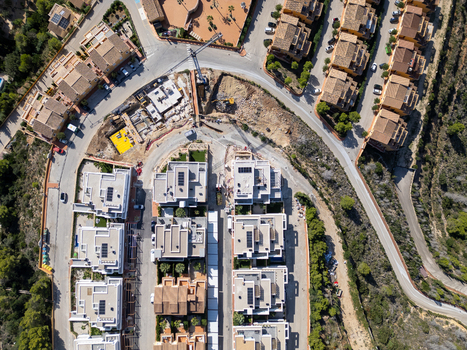 Aerial view of a residential construction site featuring modern villas ongoing road works and surrounding Mediterranean landscape in Moraira Valencian Community Spain.