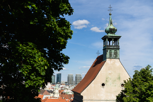 View of the historic Franciscan Church tower with a green copper spire and the modern Sky Park skyscrapers in the background in Bratislava Bratislava Region Slovakia. View of the historic Franciscan Church tower with a green copper spire and the modern Sky Park skyscrapers in the background in Bratislava Bratislava Region Slovakia.