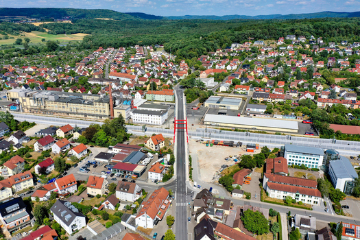 Aerial view of the red Piastenbrucke bridge spanning over railway tracks surrounded by residential houses and industrial buildings in Forchheim Bayern Germany.