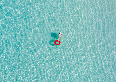 Aerial view of a person wading in crystal clear turquoise water with a red ring Vashafaru Haa Alif Atoll Maldives. Aerial view of a person wading in crystal clear turquoise water with a red ring Vashafaru Haa Alif Atoll Maldives.