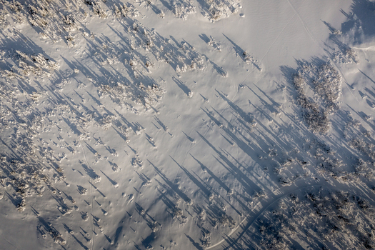 Aerial view of the snow covered landscape surrounding Gaustablikk Fjellresort with long shadows cast by pine trees across the pristine white terrain in Rjukan Telemark Norway. Aerial view of the snow covered landscape surrounding Gaustablikk Fjellresort with long shadows cast by pine trees across the pristine white terrain in Rjukan Telemark Norway.