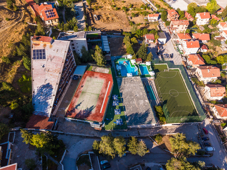Aerial view of a resort complex with a triangular hotel swimming pool tennis court and soccer field surrounded by houses and trees in Velingrad Pazardzhik Bulgaria. Aerial view of a resort complex with a triangular hotel swimming pool tennis court and soccer field surrounded by houses and trees in Velingrad Pazardzhik Bulgaria.