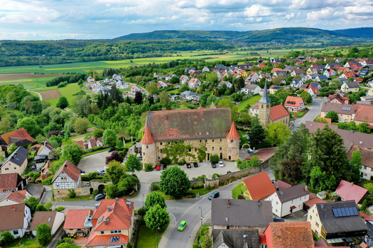Wiesenthau Germany 02 May 2026 Aerial view of Schloss Wiesenthau surrounded by traditional village houses green trees and rolling hills under a cloudy sky. Wiesenthau Germany 02 May 2026 Aerial view of Schloss Wiesenthau surrounded by traditional village houses green trees and rolling hills under a cloudy sky.