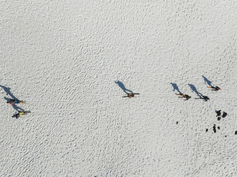 Aerial view of skiers walking across the snowy south slope of Mount Etna with long shadows on the textured white surface Nicolosi Sicilia Italy. Aerial view of skiers walking across the snowy south slope of Mount Etna with long shadows on the textured white surface Nicolosi Sicilia Italy.