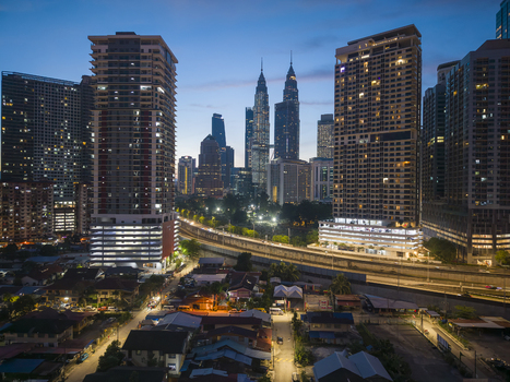 Kuala Lumpur Malaysia 11 March 2026 Aerial view of the Petronas Twin Towers and the city skyline with illuminated skyscrapers and residential areas at twilight.