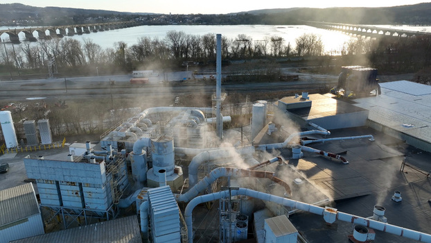 Aerial view of an industrial facility with piping and steam emissions located near the Susquehanna River and bridge at sunset in Columbia Pennsylvania United States. Aerial view of an industrial facility with piping and steam emissions located near the Susquehanna River and bridge at sunset in Columbia Pennsylvania United States.