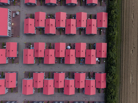 Aerial view of prefabricated housing for migrant and seasonal workers with uniform red roofs and paved pathways in Swifterbant Flevoland Netherlands. Aerial view of prefabricated housing for migrant and seasonal workers with uniform red roofs and paved pathways in Swifterbant Flevoland Netherlands.