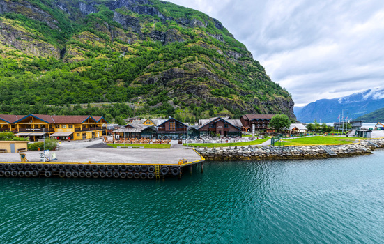 Aerial view of the village of Flam with its wooden buildings harbor and steep green mountains along the fjord in Flam Vestland Norway. Aerial view of the village of Flam with its wooden buildings harbor and steep green mountains along the fjord in Flam Vestland Norway.