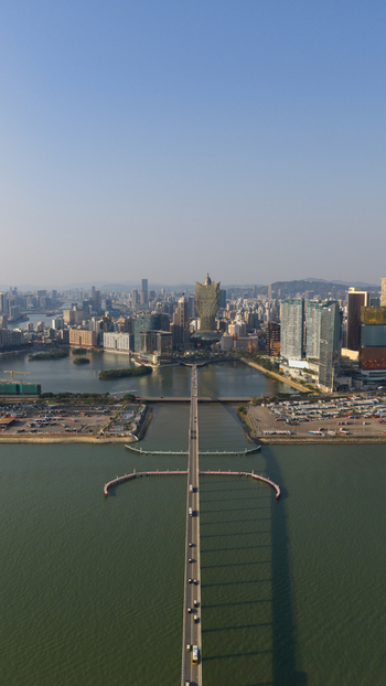 Macao 18 February 2026 Aerial view of the Grand Lisboa and Macau skyline featuring the long bridge modern skyscrapers and calm coastal waters under a clear sky. Macao 18 February 2026 Aerial view of the Grand Lisboa and Macau skyline featuring the long bridge modern skyscrapers and calm coastal waters under a clear sky.