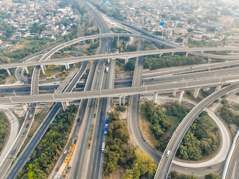 Aerial view of the Cikunir highway interchange featuring complex multi level concrete overpasses flowing traffic and surrounding lush greenery in Kecamatan Bekasi Selatan Jawa Barat Indonesia. Aerial view of the Cikunir highway interchange featuring complex multi level concrete overpasses flowing traffic and surrounding lush greenery in Kecamatan Bekasi Selatan Jawa Barat Indonesia.