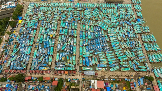 Aerial view of Malpe Fishing Harbour with hundreds of colorful fishing boats docked in rows creating a vibrant pattern on the water in Udupi Karnataka India. Aerial view of Malpe Fishing Harbour with hundreds of colorful fishing boats docked in rows creating a vibrant pattern on the water in Udupi Karnataka India.