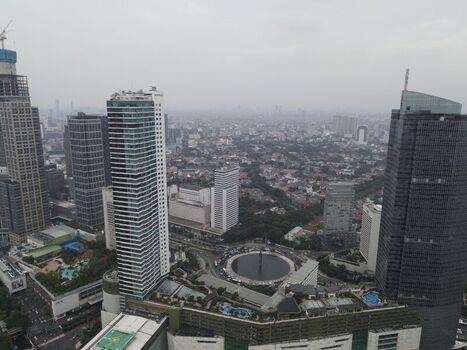 Aerial view of the modern skyline of Jakarta Pusat featuring tall skyscrapers a prominent circular fountain and dense urban development in Kecamatan Menteng Daerah Khusus Ibukota Indonesia. Aerial view of the modern skyline of Jakarta Pusat featuring tall skyscrapers a prominent circular fountain and dense urban development in Kecamatan Menteng Daerah Khusus Ibukota Indonesia.