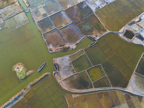 Aerial view of geometric salt pans and narrow water channels with traditional wooden boats in Moheskhali Upazila Chittagong Division Bangladesh. Aerial view of geometric salt pans and narrow water channels with traditional wooden boats in Moheskhali Upazila Chittagong Division Bangladesh.