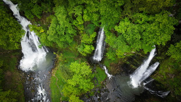 Aerial view of the Cascades du Flumen waterfalls cascading through a lush green forest into rocky pools in Septmoncel Les Molunes Bourgogne Franche Comte France. Aerial view of the Cascades du Flumen waterfalls cascading through a lush green forest into rocky pools in Septmoncel Les Molunes Bourgogne Franche Comte France.
