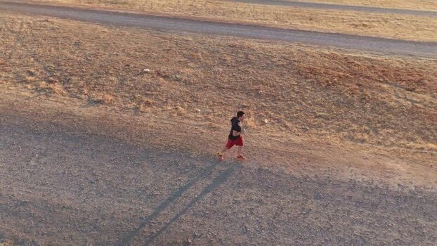 Aerial view of a man running on a dirt path in Caceres Spain.