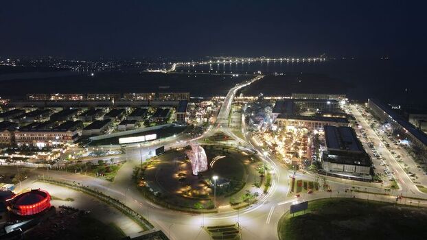 Aerial view of the Orchestra sculpture in the roundabout at Golf Island PIK with illuminated streets and modern buildings in Kecamatan Penjaringan Daerah Khusus Ibukota Indonesia. Aerial view of the Orchestra sculpture in the roundabout at Golf Island PIK with illuminated streets and modern buildings in Kecamatan Penjaringan Daerah Khusus Ibukota Indonesia.