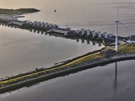 Den Oever Netherlands 19 June 2026 Aerial view of the Stevinsluizen locks with dams fish friendly pumping stations and a wind turbine in the early morning light. Den Oever Netherlands 19 June 2026 Aerial view of the Stevinsluizen locks with dams fish friendly pumping stations and a wind turbine in the early morning light.