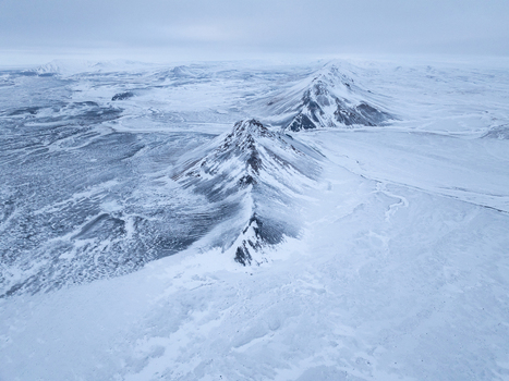 Aerial view of snow covered mountain peaks and vast icy plains under a cloudy sky in the remote wilderness Egilsstadir Mulathing Iceland. Aerial view of snow covered mountain peaks and vast icy plains under a cloudy sky in the remote wilderness Egilsstadir Mulathing Iceland.