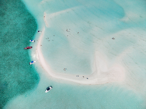 Aerial view of Man O War Cay Sandbar with people walking on white sand and boats anchored in turquoise water in Rolletown Exuma The Bahamas. Aerial view of Man O War Cay Sandbar with people walking on white sand and boats anchored in turquoise water in Rolletown Exuma The Bahamas.