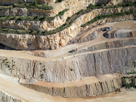 Aerial view of a quarry with terraced rock faces dirt roads and heavy machinery working on the site in Teulada Valencian Community Spain.