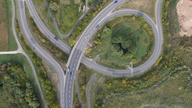 Aerial view of a highway interchange with a circular ramp surrounded by lush green trees and rural fields in Grossheubach Bavaria Germany. Aerial view of a highway interchange with a circular ramp surrounded by lush green trees and rural fields in Grossheubach Bavaria Germany.