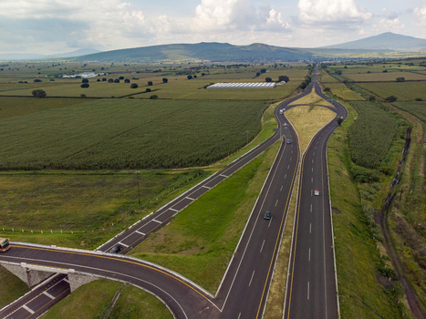 Aerial view of the Autopista Mexico Guadalajara highway interchange surrounded by lush agricultural fields and green landscape under a cloudy sky in Ecuandureo Michoacan Mexico. Aerial view of the Autopista Mexico Guadalajara highway interchange surrounded by lush agricultural fields and green landscape under a cloudy sky in Ecuandureo Michoacan Mexico.