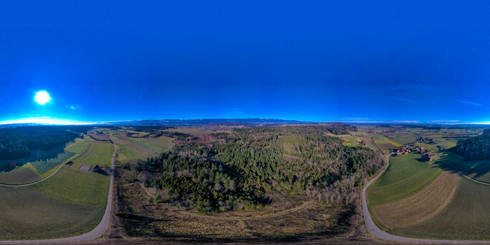 Aerial view of the rural landscape in the Seeland District featuring dense forests and agricultural fields under a clear blue sky Grossaffoltern Bern Switzerland. Aerial view of the rural landscape in the Seeland District featuring dense forests and agricultural fields under a clear blue sky Grossaffoltern Bern Switzerland.