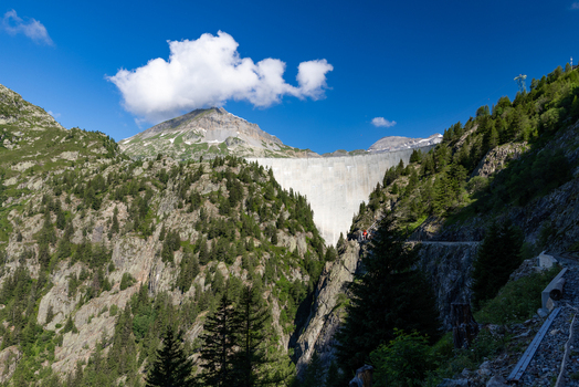 View of the Emosson Dam surrounded by steep pine covered mountains under a clear blue sky in Le Chatelard Fribourg Switzerland. View of the Emosson Dam surrounded by steep pine covered mountains under a clear blue sky in Le Chatelard Fribourg Switzerland.