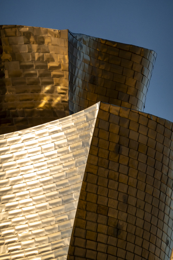 View of the golden sunlight reflecting off the curved titanium panels of the Guggenheim Museum Bilbao Euskadi Spain. View of the golden sunlight reflecting off the curved titanium panels of the Guggenheim Museum Bilbao Euskadi Spain.