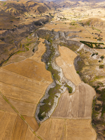 Aerial view of Toachi River Canyon surrounded by dry golden agricultural fields and rugged terrain in Zumbahua Cotopaxi Ecuador. Aerial view of Toachi River Canyon surrounded by dry golden agricultural fields and rugged terrain in Zumbahua Cotopaxi Ecuador.